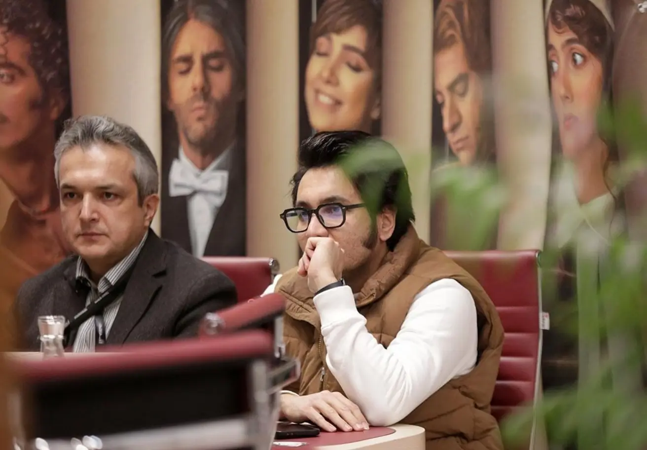 farahang_two_men_chating_on_dobe_posters_of_pop_stars_behin_9a030ed4